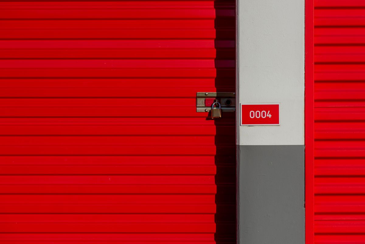 Red metal storage unit door with padlock and unit number