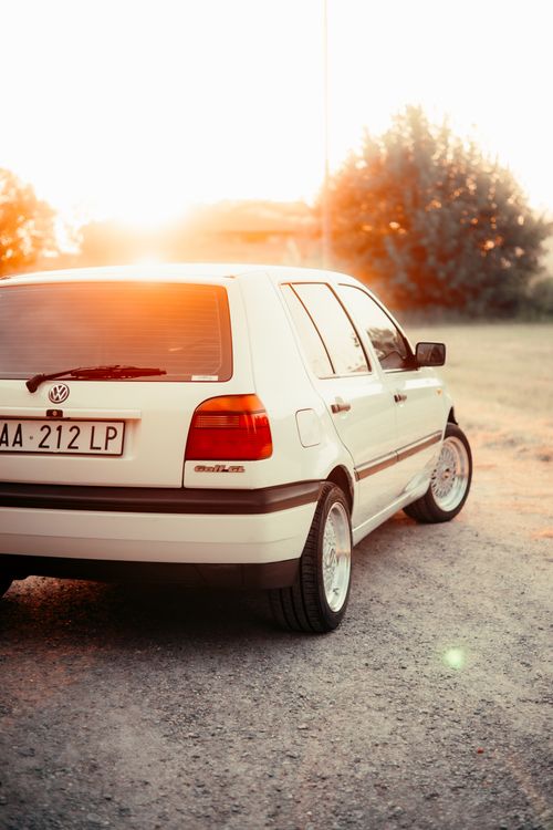 Free A classic white car parked outdoors during sunset, capturing a nostalgic and warm ambiance. Stock Photo