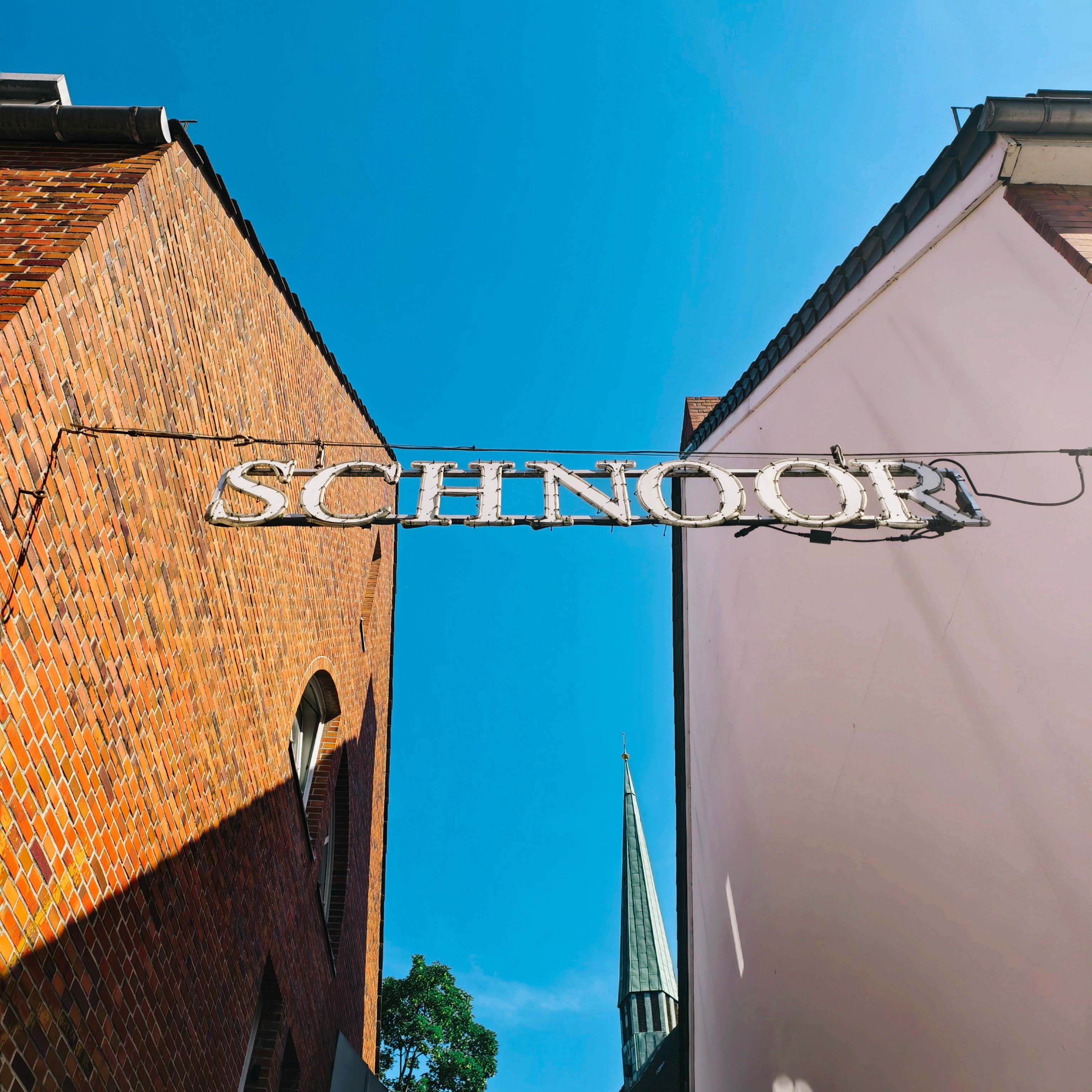 View of Schnoor Quarter sign between buildings under a clear blue sky in Bremen, Germany.