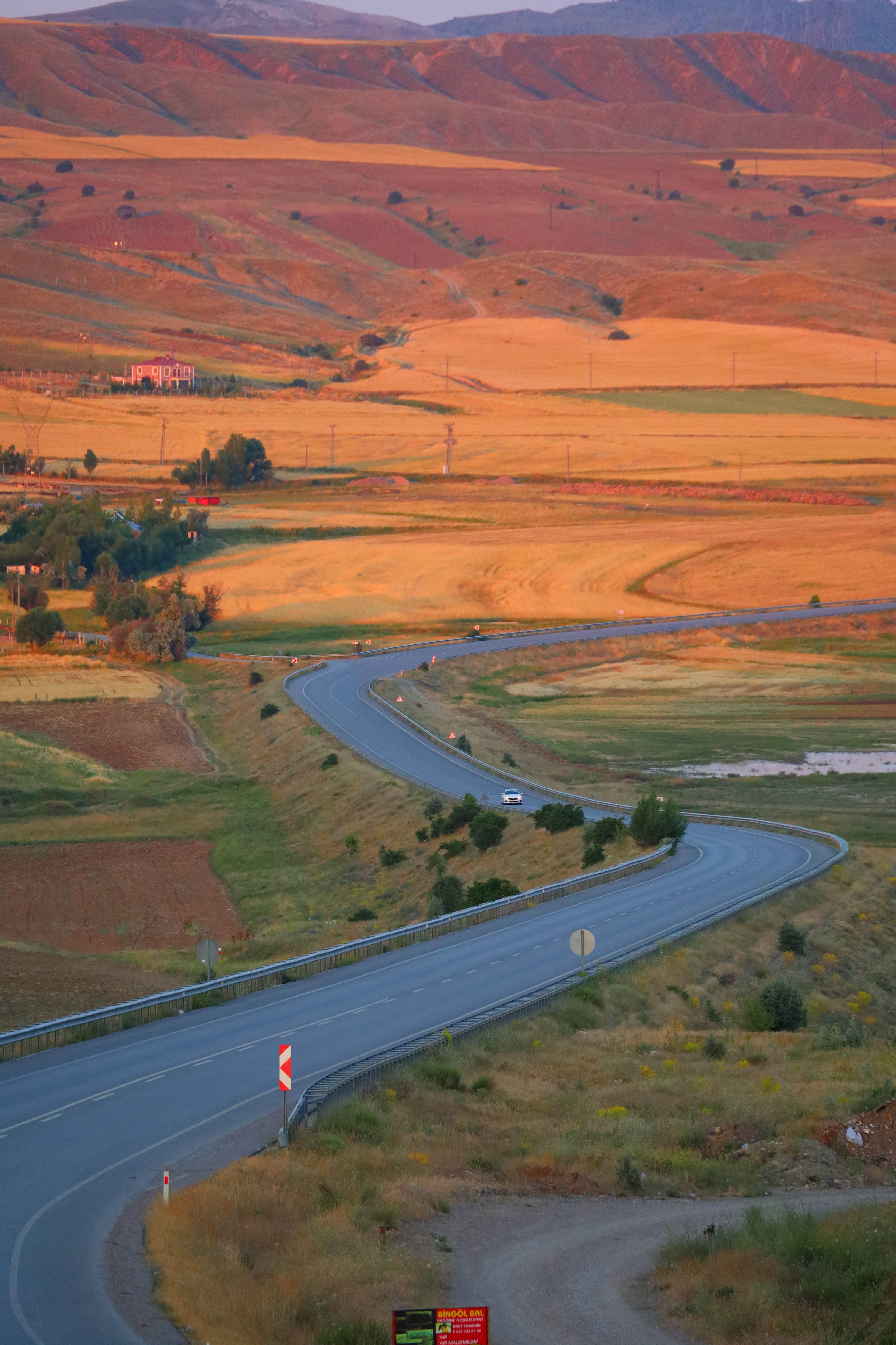 A beautiful sunset view of a winding road through rural hills and fields, evoking tranquility.