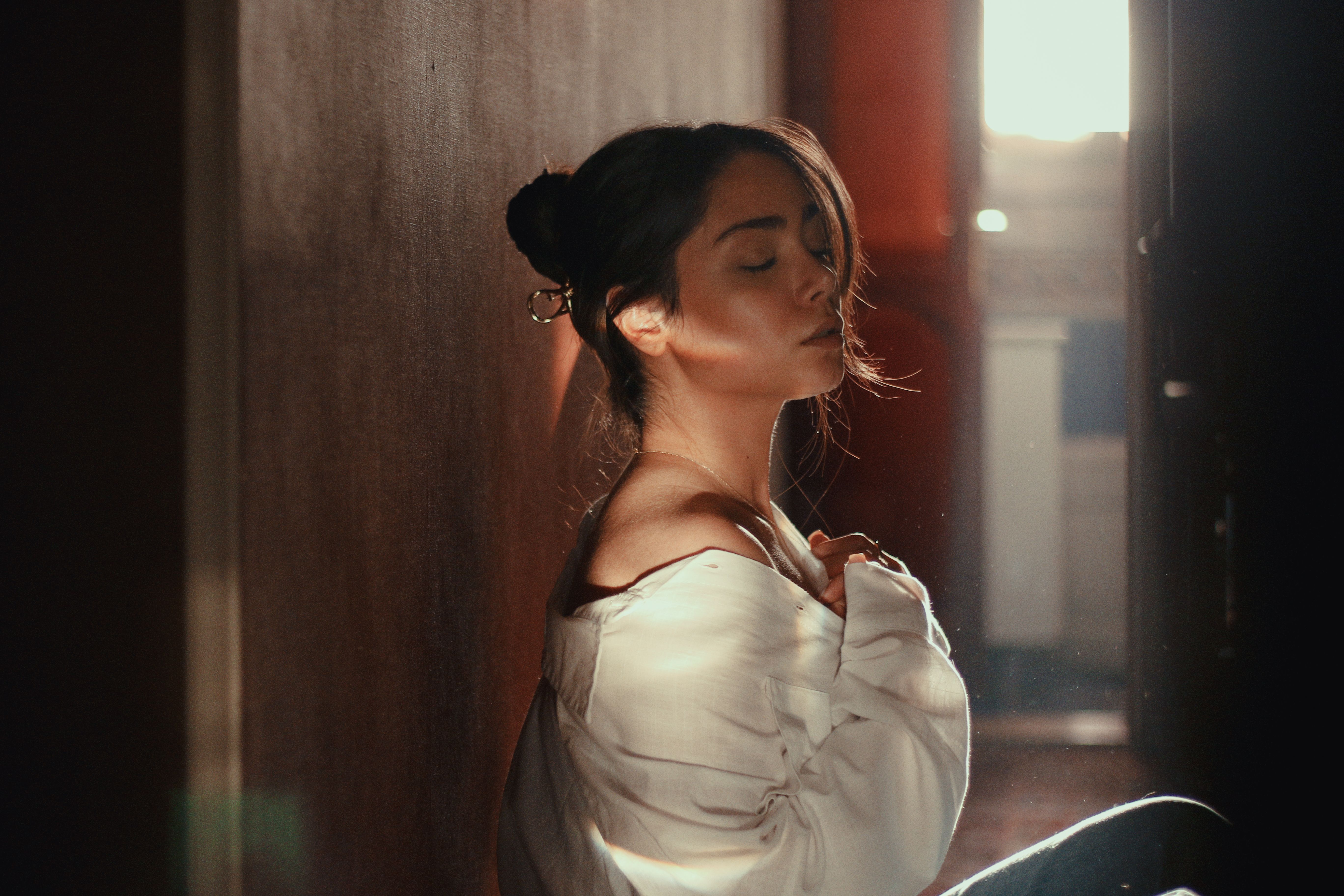 A young woman in soft light creates a serene and intimate ambiance indoors.