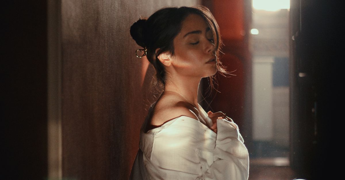 A young woman in soft light creates a serene and intimate ambiance indoors.