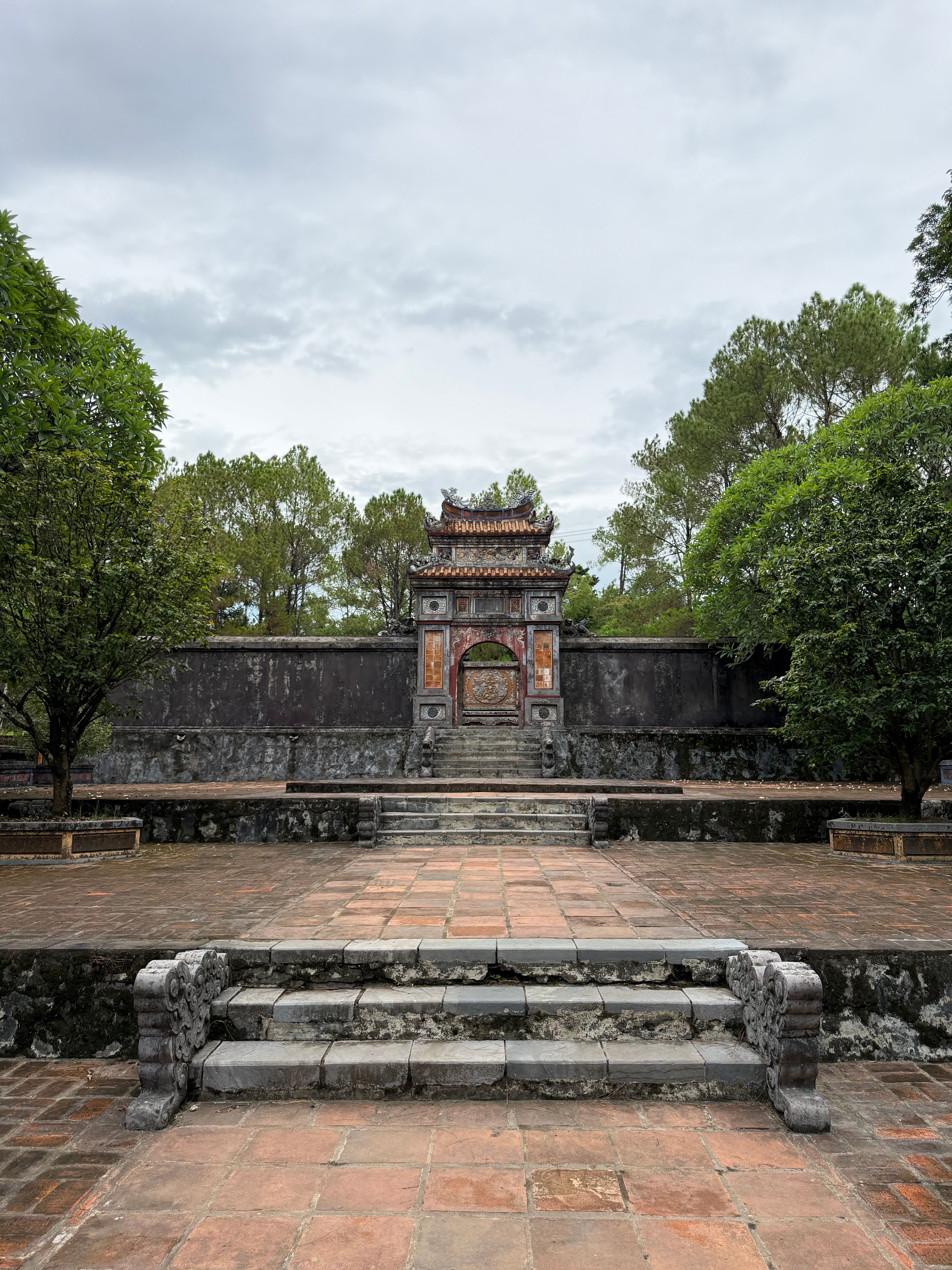 Beautiful view of the ancient gate at Tự Đức Tomb, Hue, surrounded by lush greenery.