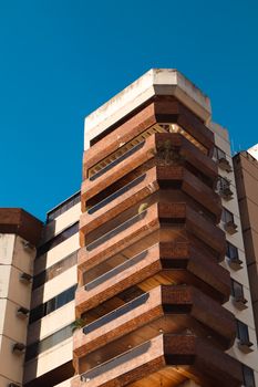 Upward view of a modern brick building in Goiânia against a vibrant blue sky.