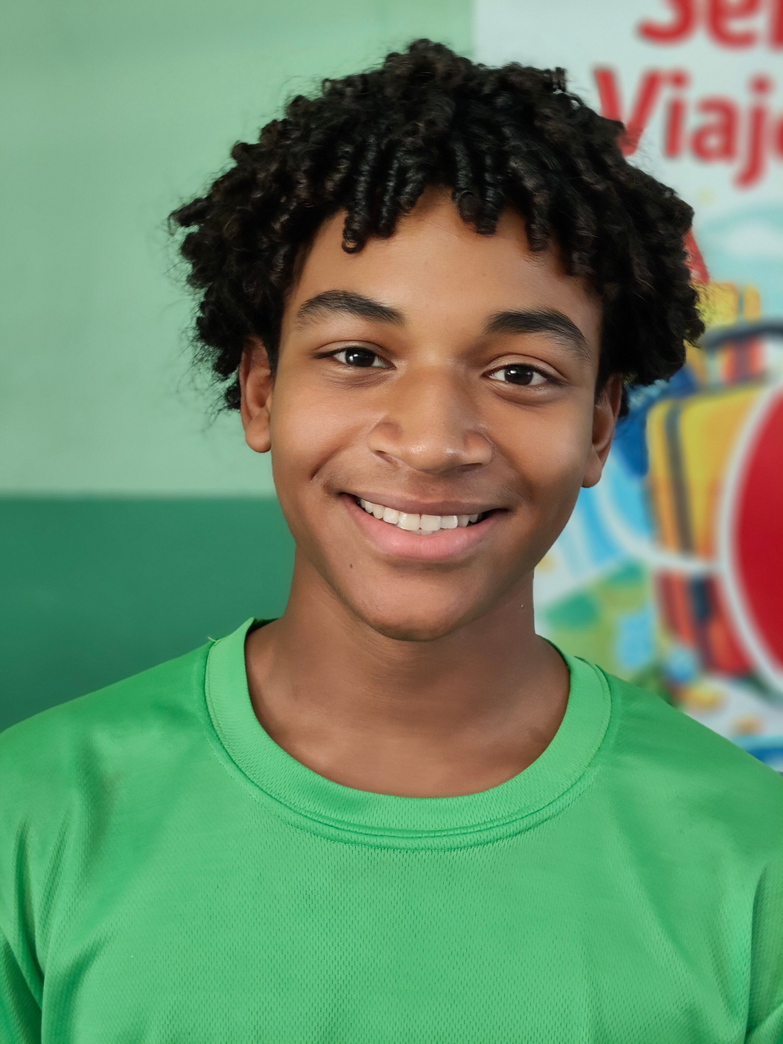 Portrait of a smiling teenage boy in a green shirt. Bright and cheerful mood.