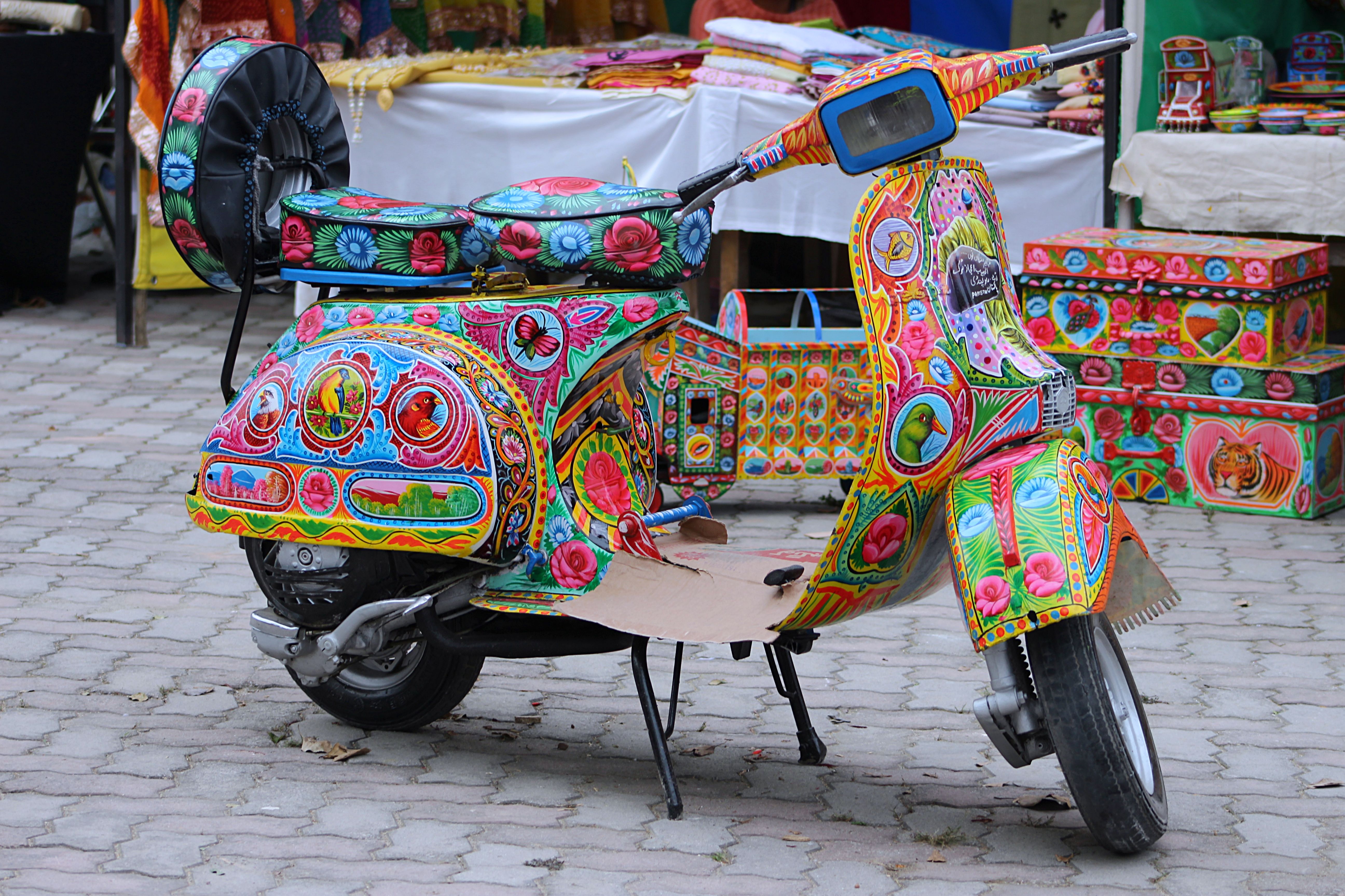 Vibrant Vespa scooter adorned with traditional Pakistani truck art, showcasing cultural motifs and bright colors.