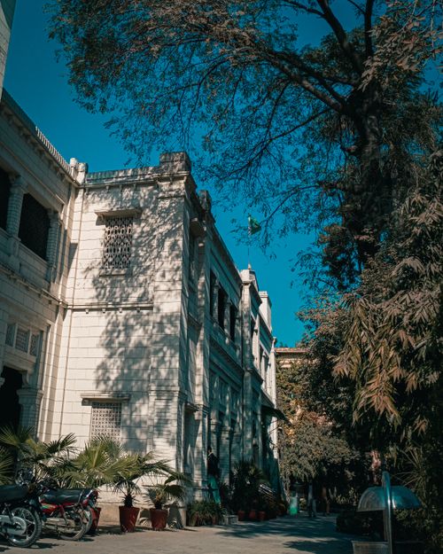 Free Beautiful view of a historic colonial-style building surrounded by trees under a bright blue sky. Stock Photo