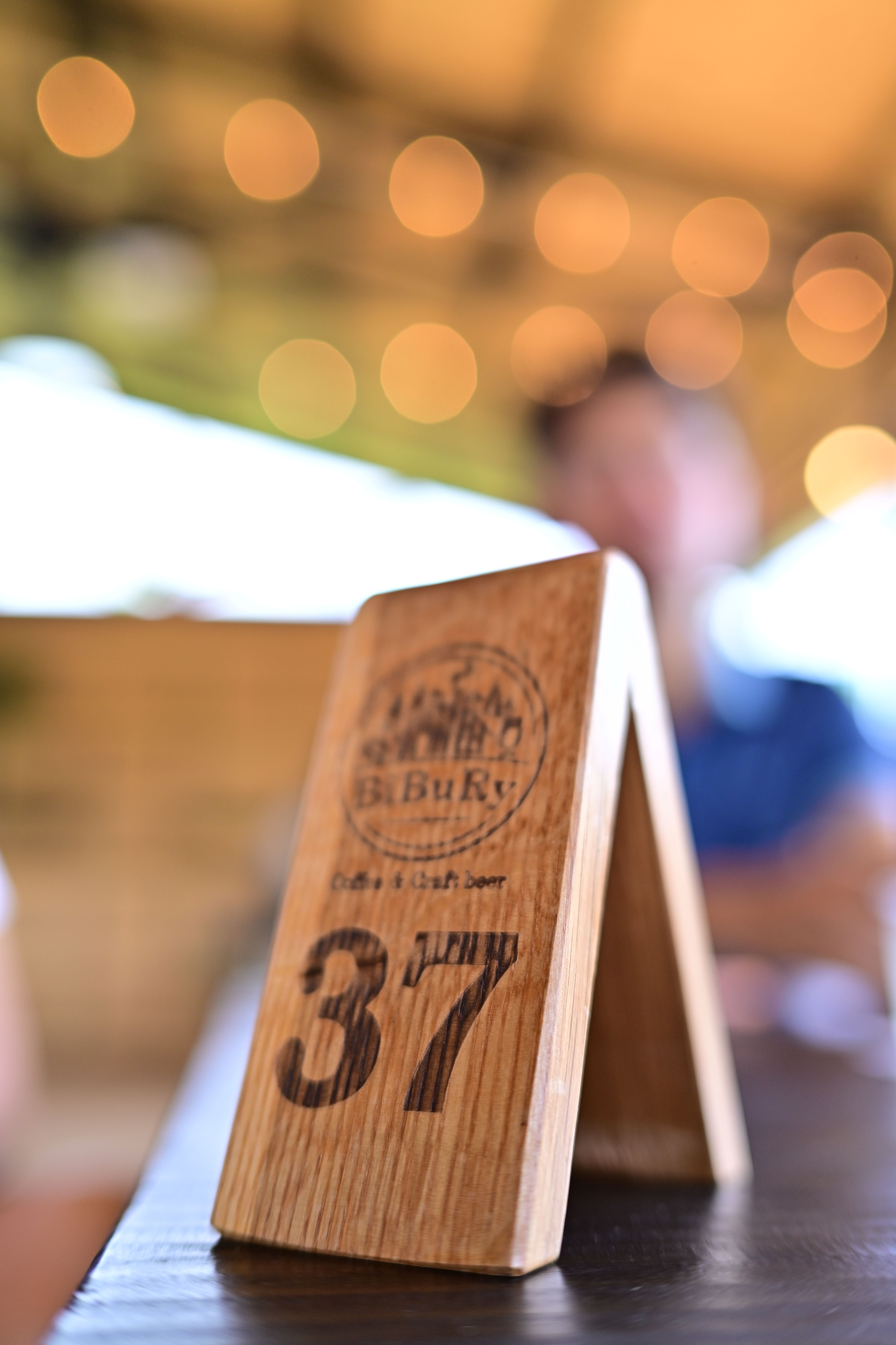 Elegant wooden table number 37 with blurred cafe background featuring bokeh lights.
