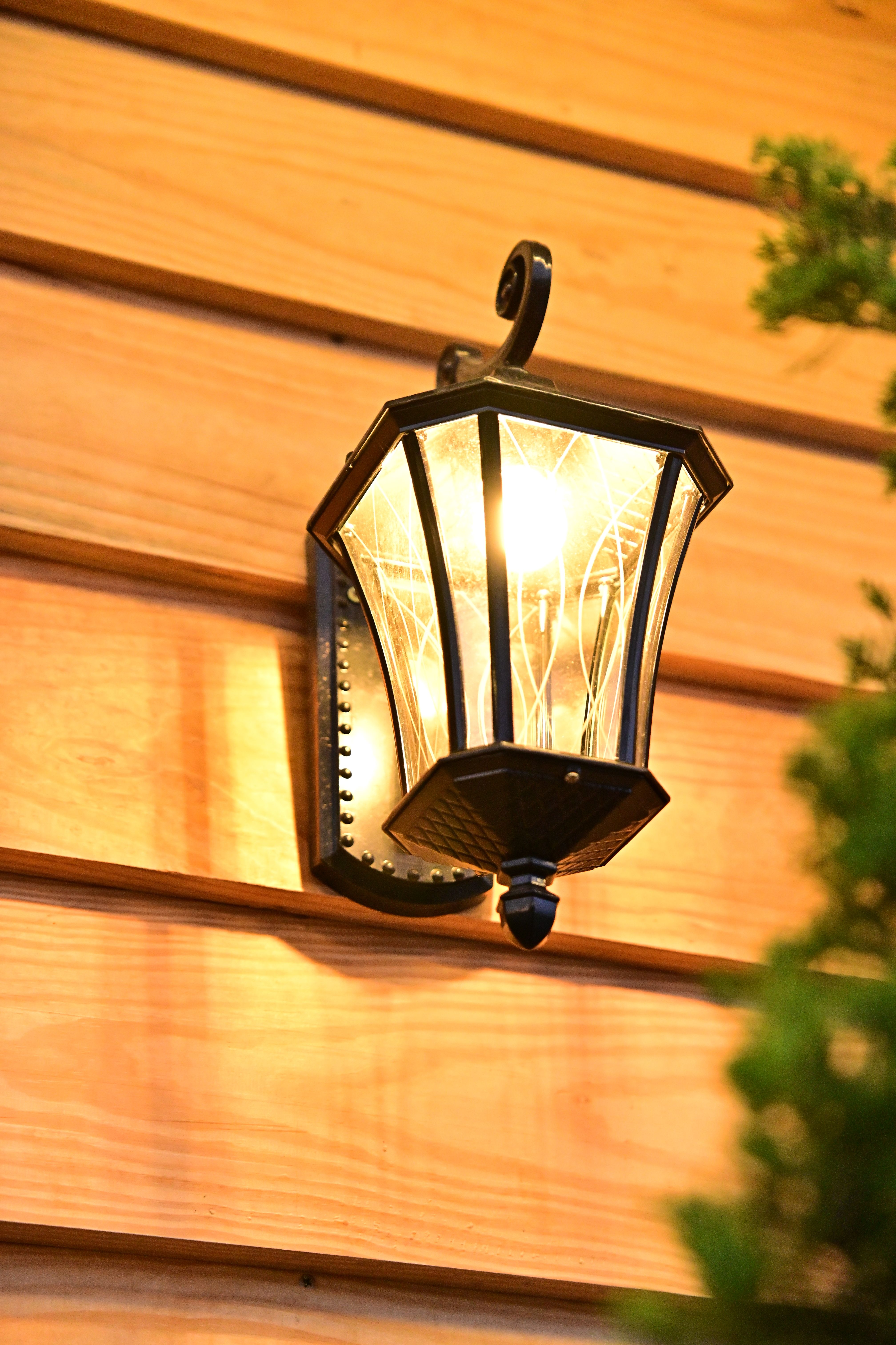 A warm-lit outdoor lantern mounted on a wooden wall adds rustic charm.