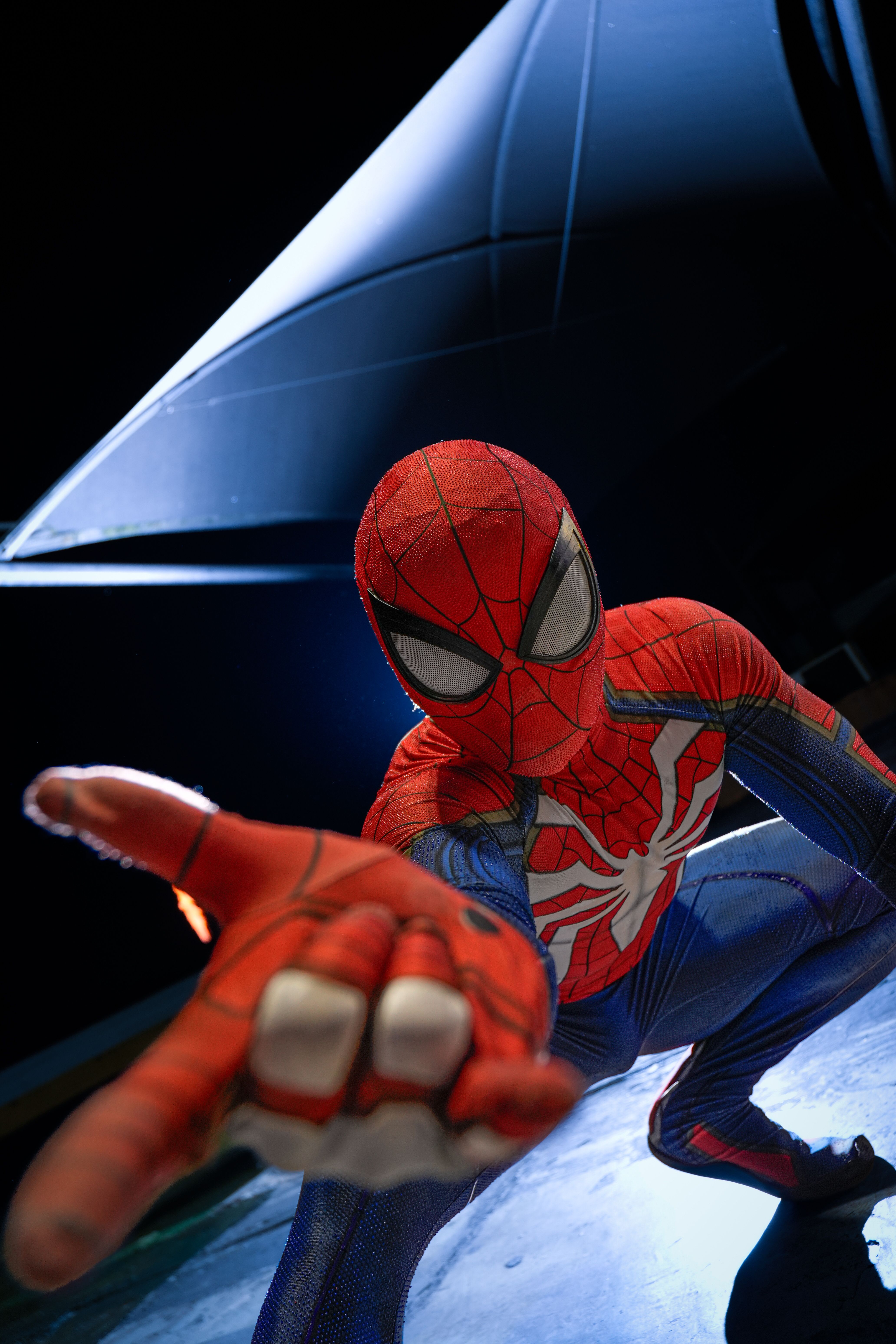 A cosplayer in a superhero costume striking a dynamic, action-packed pose indoors.