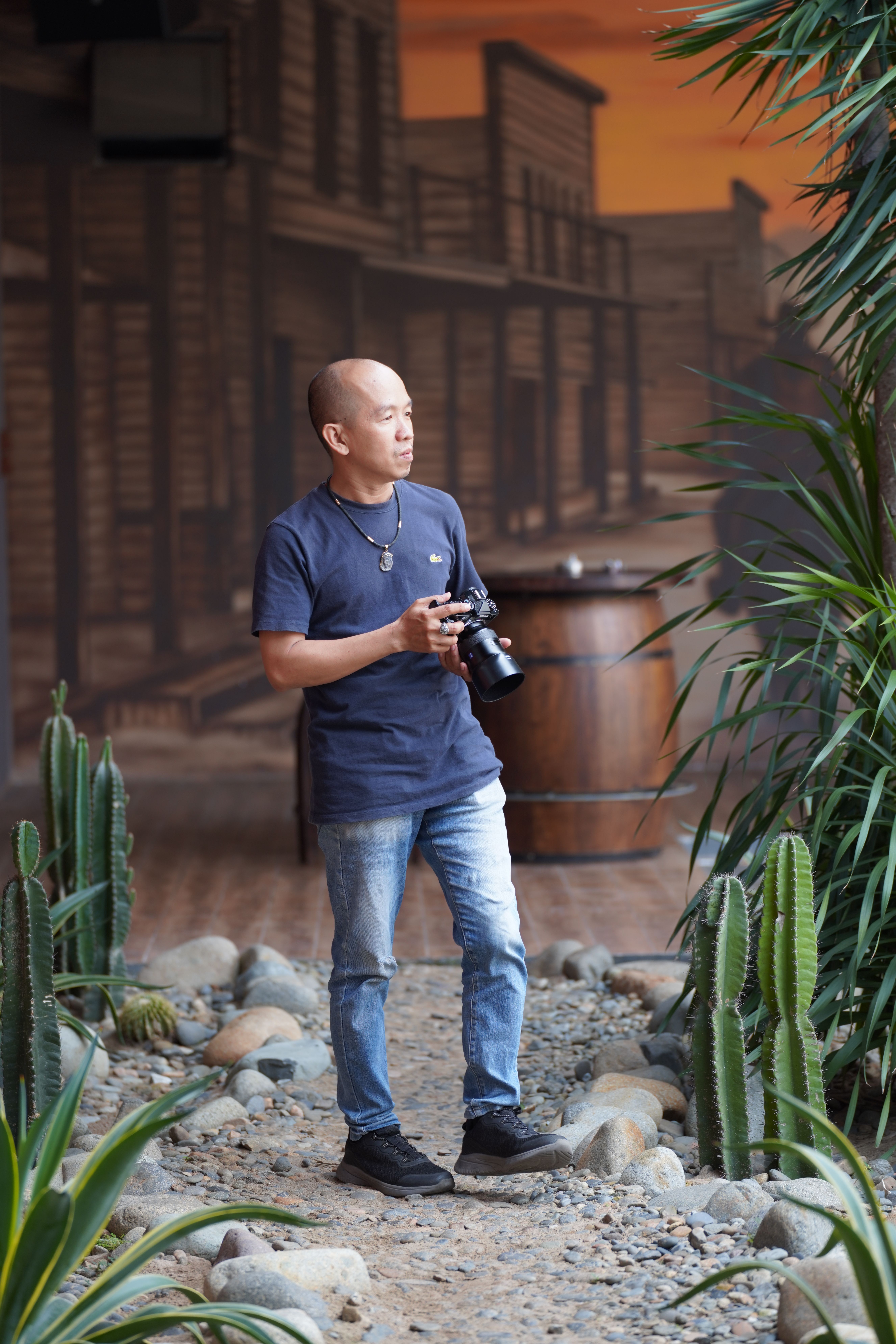 A photographer explores a rustic setting with a camera, surrounded by cacti and natural elements.