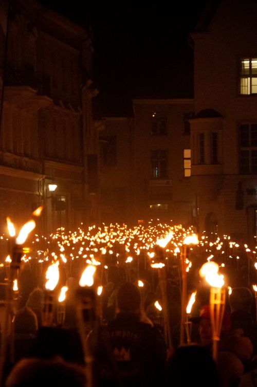 Free Back view crowd of unrecognizable people walking on street with burning torches during procession at night Stock Photo