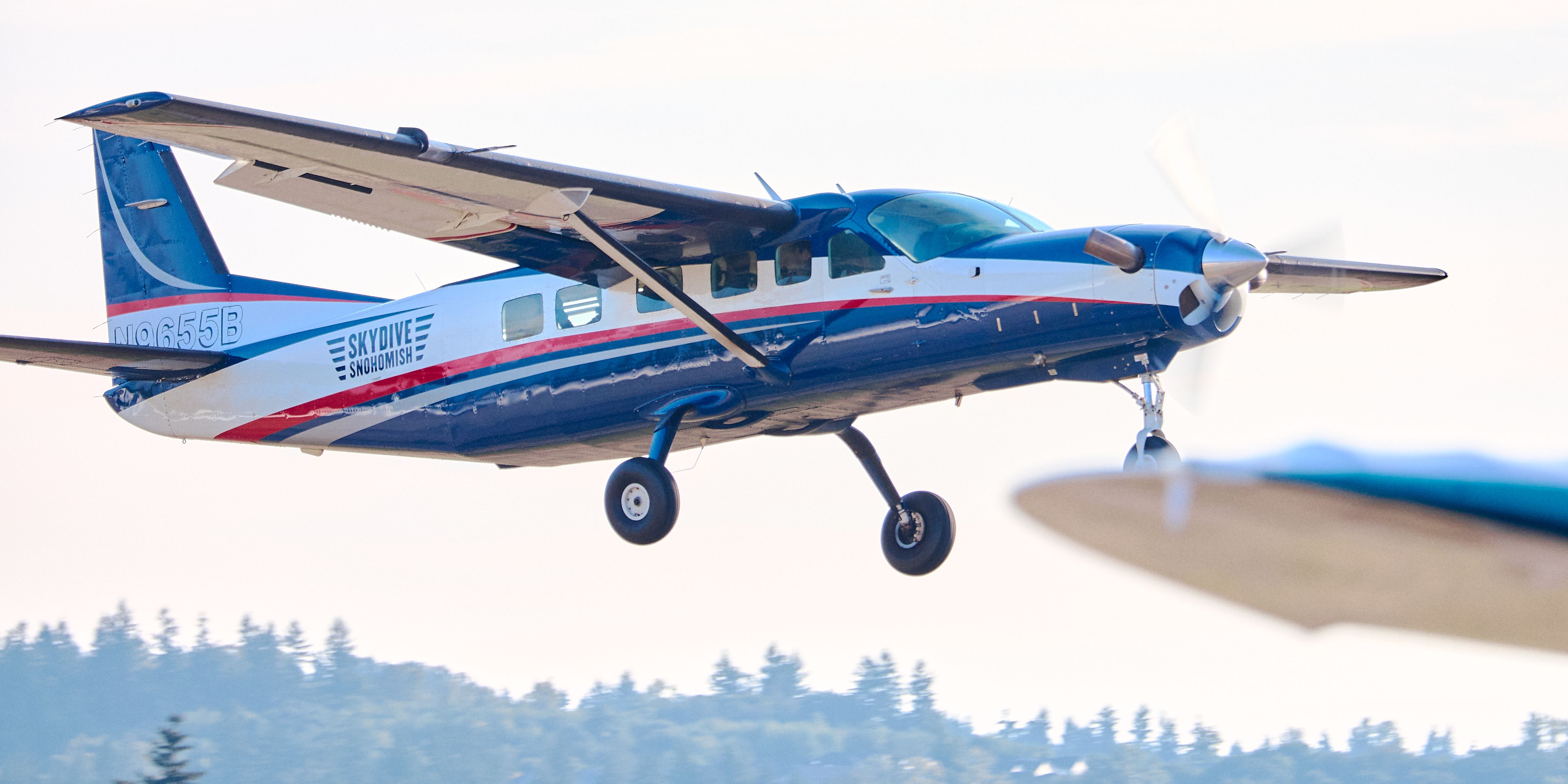 A small plane prepares for landing with clear blue skies in the background.