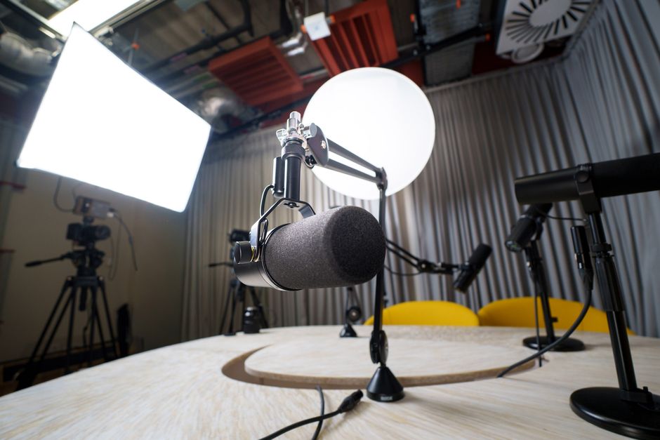 A modern podcast recording studio with microphones, chairs, and lighting equipment.