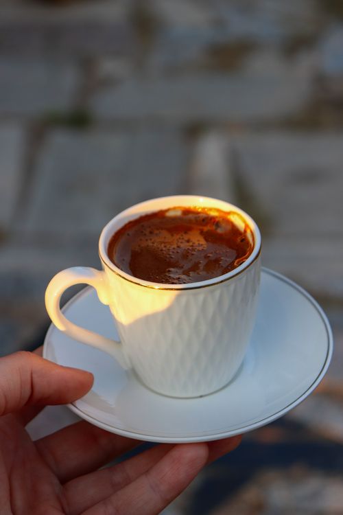 Free A close-up of a hand holding a cup of Turkish coffee in a white cup with a saucer. Ideal for food and lifestyle themes. Stock Photo