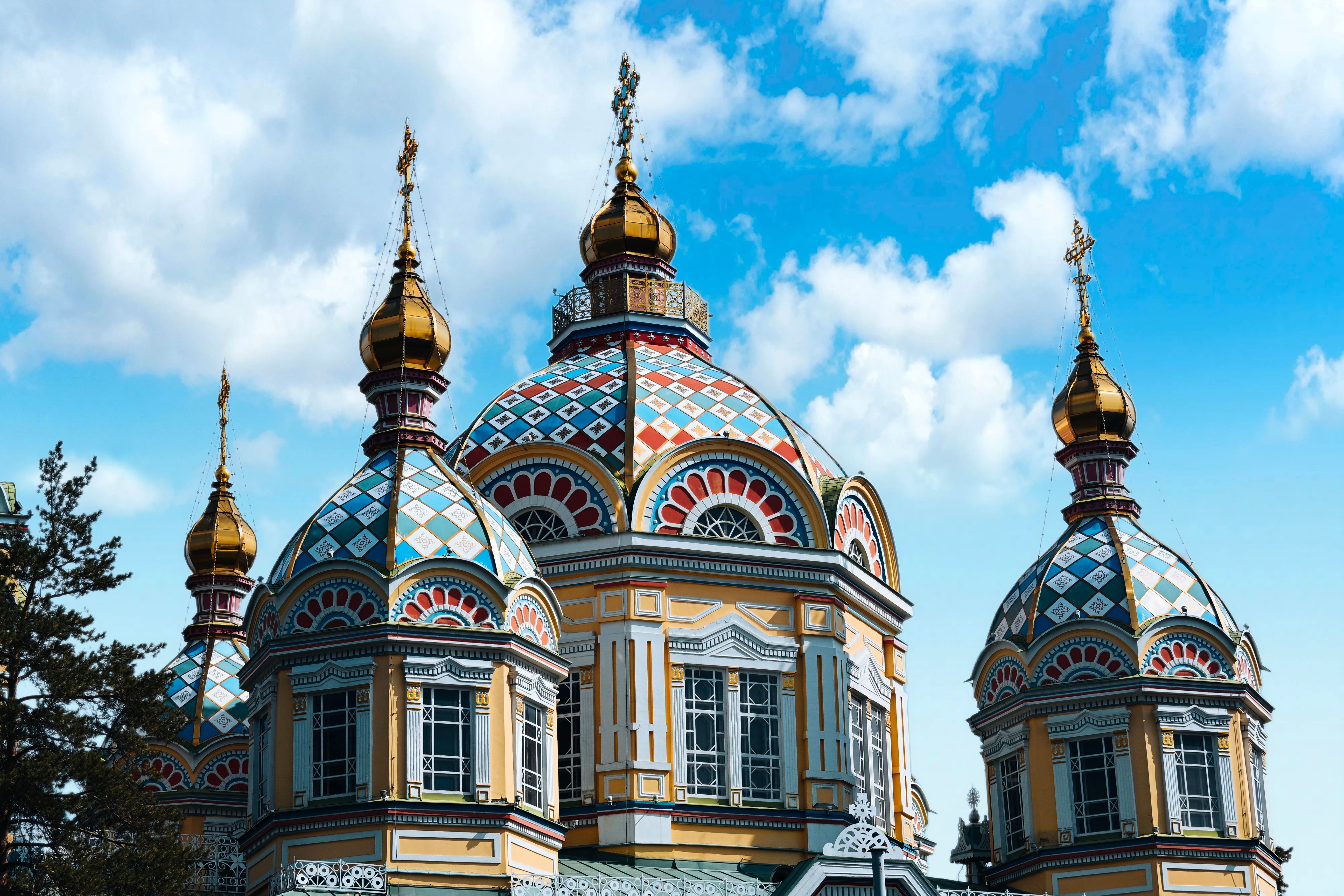 Colorful domes of the Ascension Cathedral in Almaty against a blue sky.