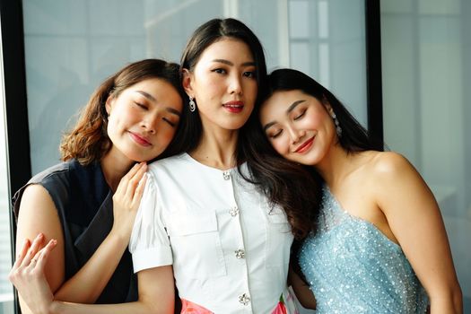 Three smiling women embracing indoors, exuding warmth and friendship.