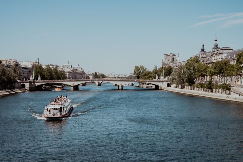 Sunny view of a tour boat cruising along the River Seine in France with a clear sky