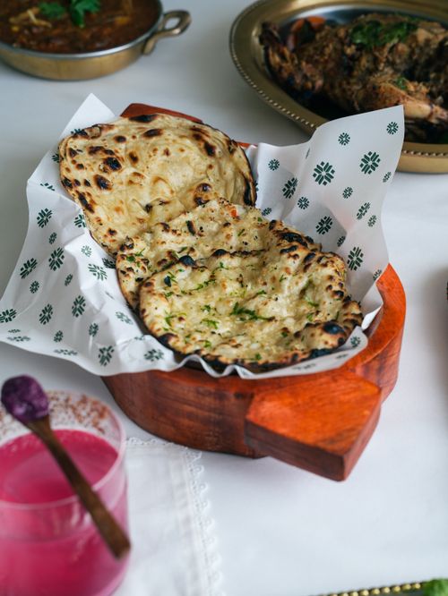 Free Tantalizing Indian garlic naan served with curry and pink drink. Stock Photo