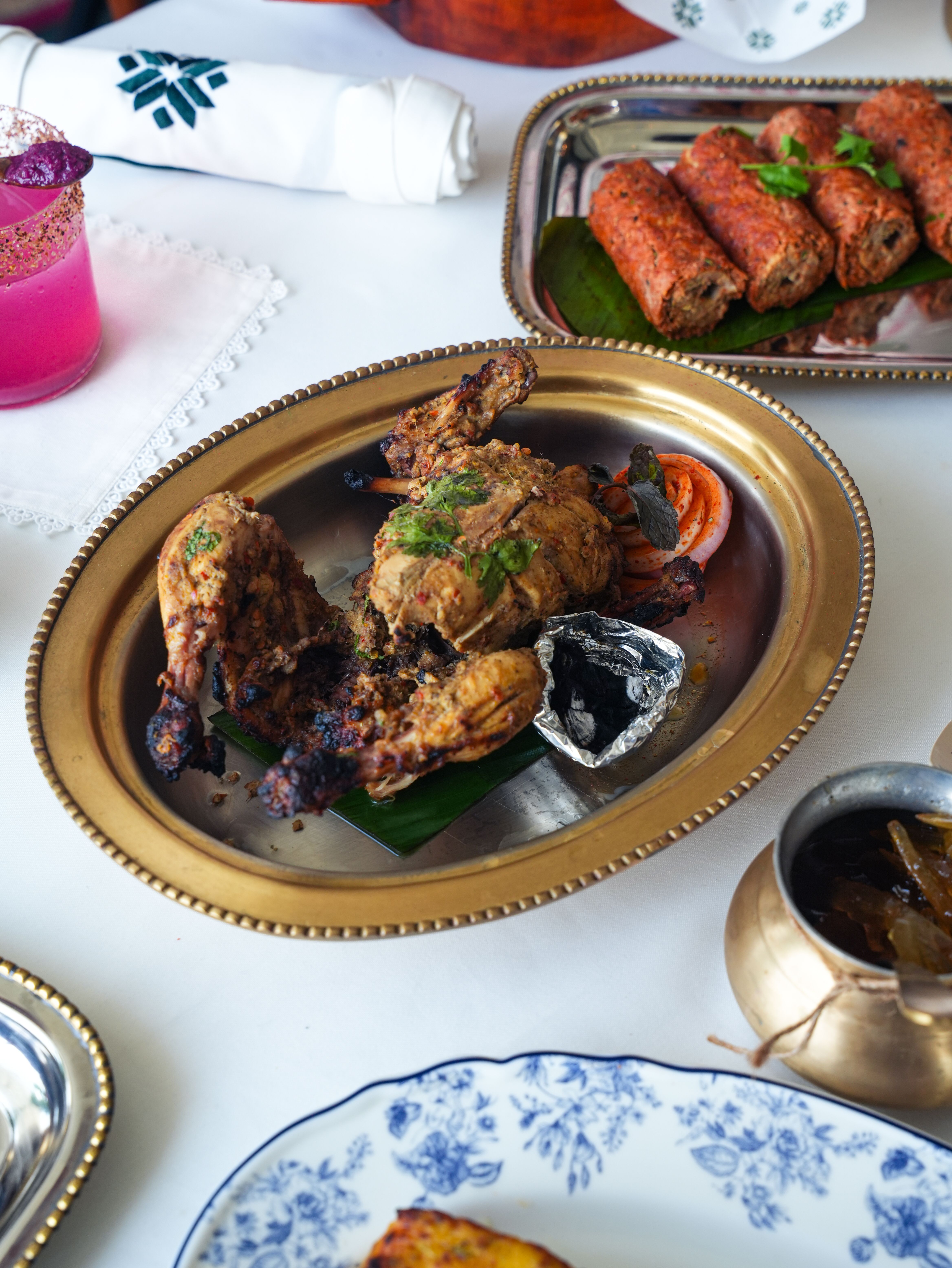 A delicious Indian platter featuring grilled chicken, kebabs, and a refreshing drink, ideal for festive occasions.