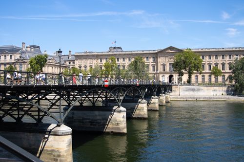 Free Scenic view of the Pont des Arts bridge with Louvre in background during summer in Paris, France. Stock Photo