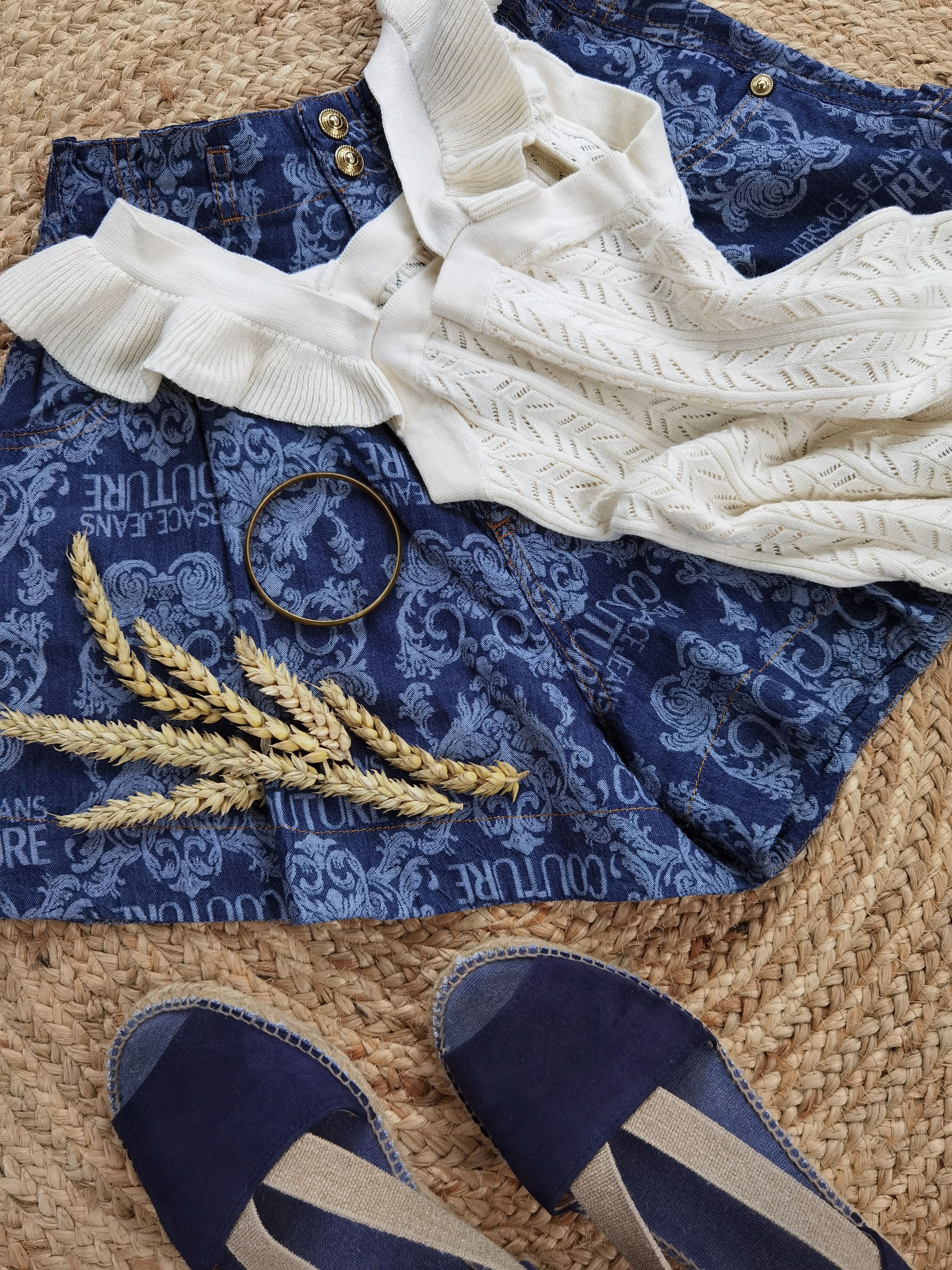 Flat lay of a chic blue and white casual outfit with accessories and wheat stalks.