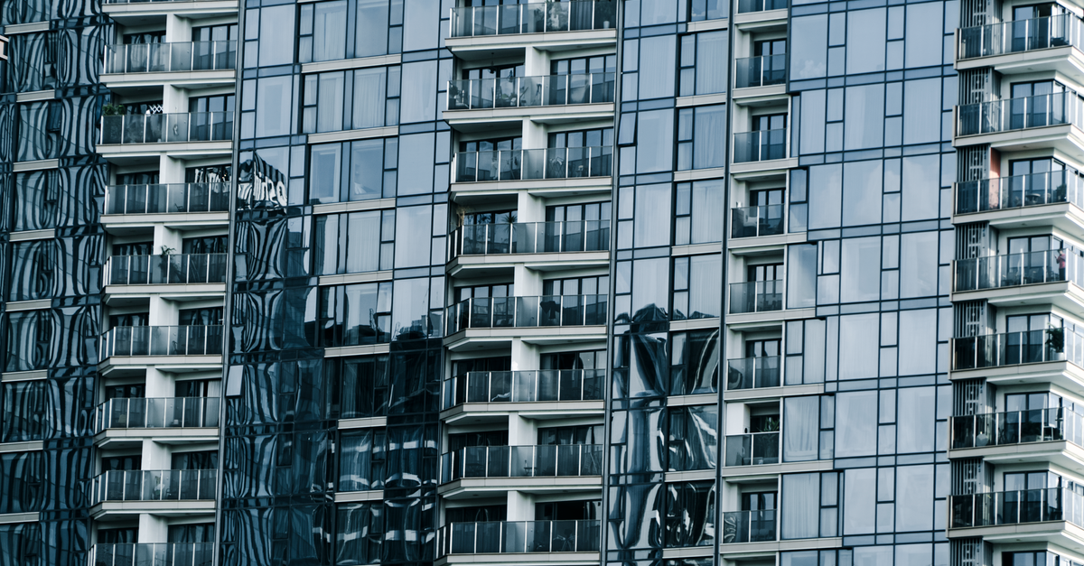 High-rise building with glass facade reflecting surroundings.