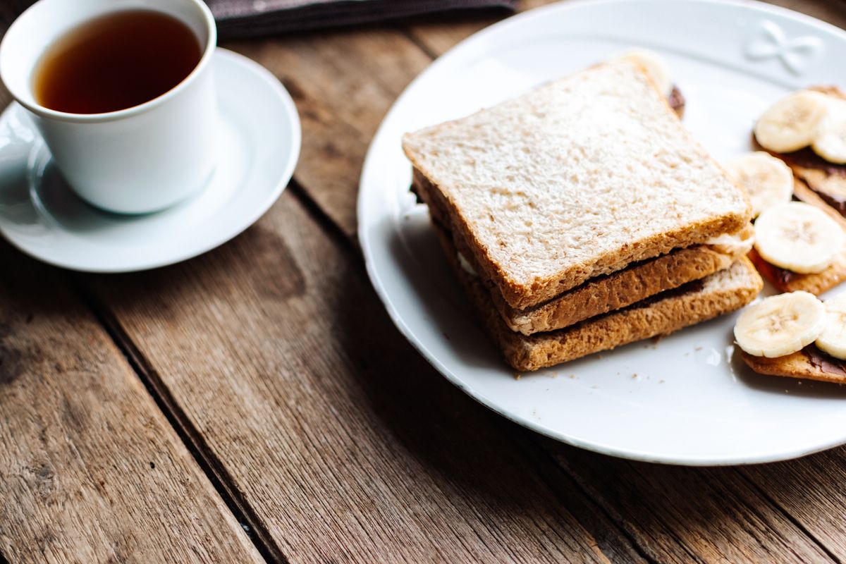 Toast with banana slices and a cup of tea on a wooden table