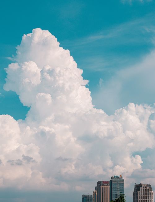 Free Dramatic cumulus clouds extending over a vibrant city skyline with modern buildings. Stock Photo