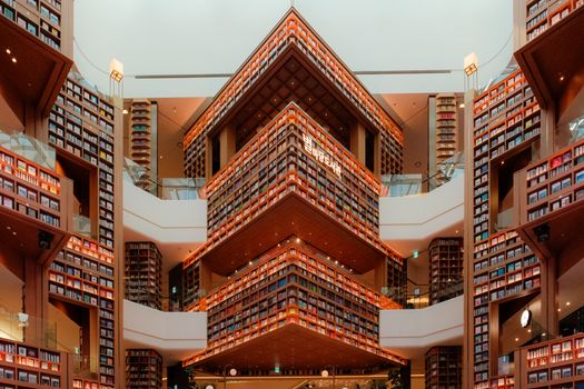 Vibrant and expansive modern library interior with geometric bookshelves and warm lighting.