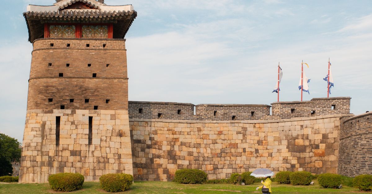 A person walks by the iconic Suwon Hwaseong Fortress on a clear day in Korea. visual (Photo: Henry Acevedo / Pexels)