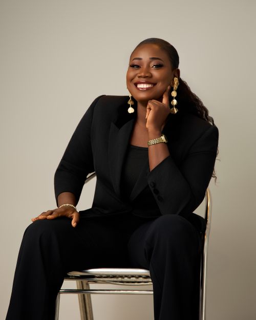 Free Confident woman in black suit sitting, smiling warmly. Stock Photo