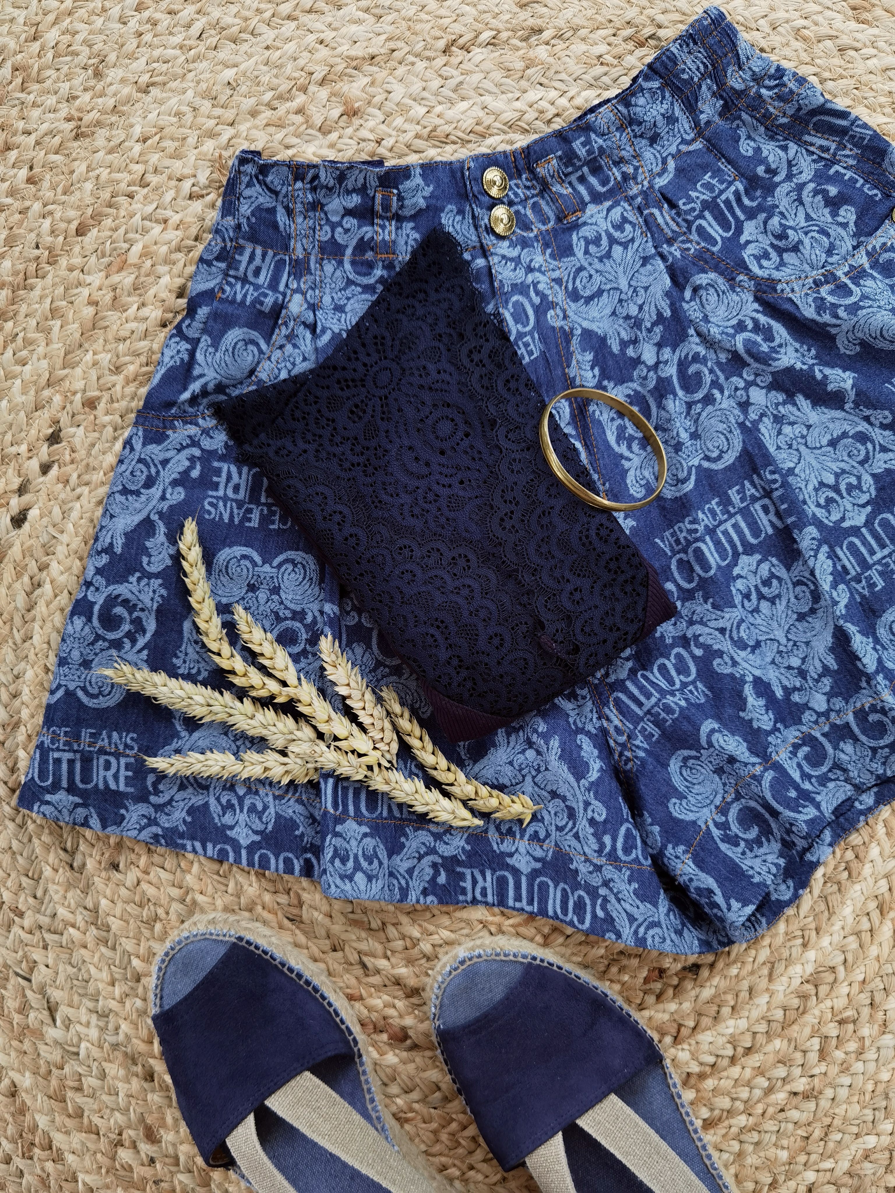 Elegant navy blue shorts and shoes flat lay with accessories on woven mat.