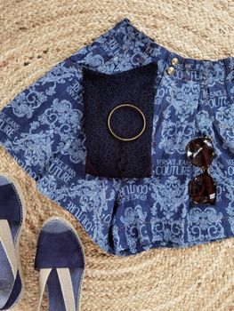 Flat lay of summer fashion with denim shorts, sunglasses, and espadrilles.