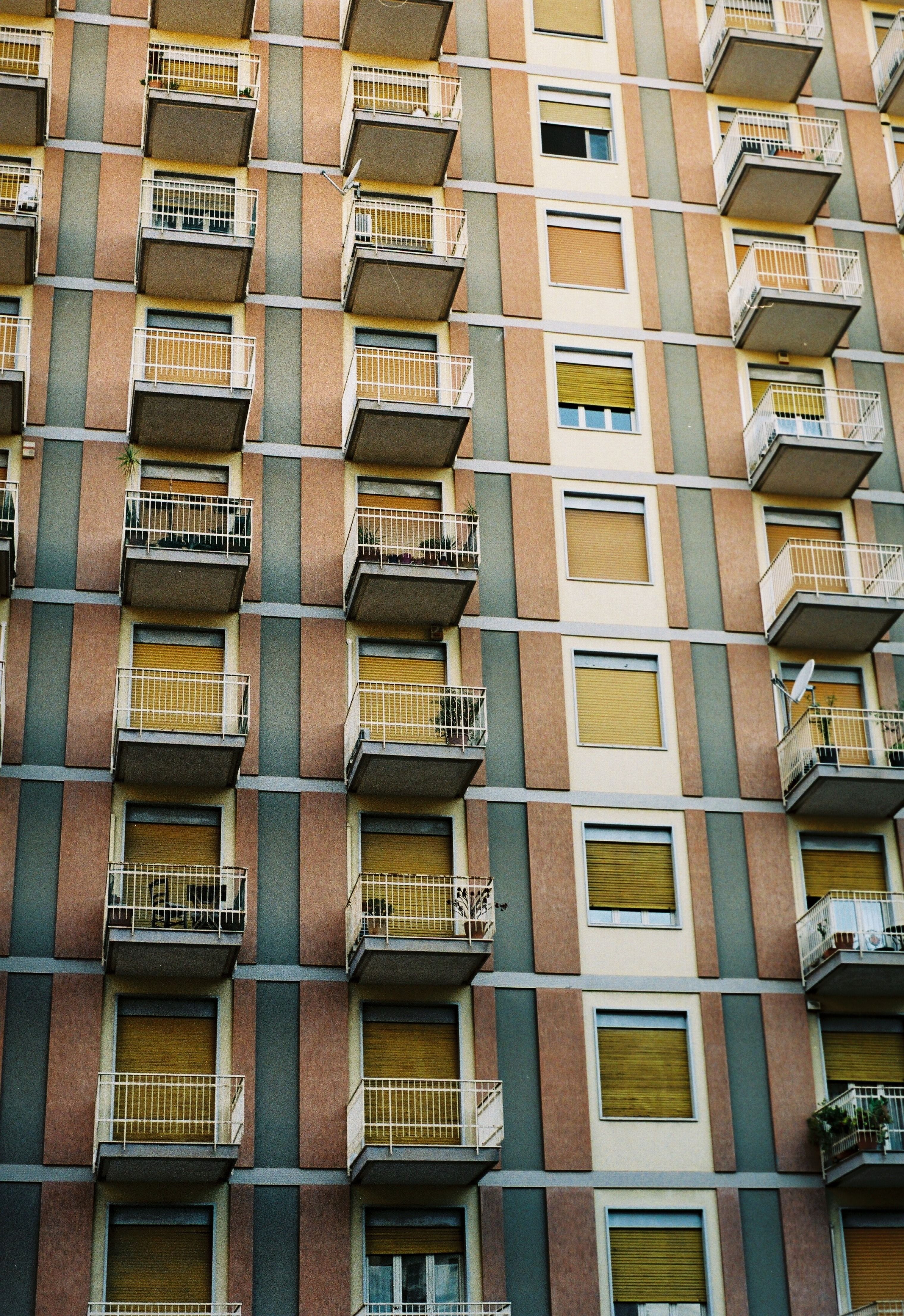 Close-up of a modern high-rise apartment building with balconies and closed shutters.