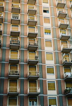 Close-up of a modern high-rise apartment building with balconies and closed shutters.