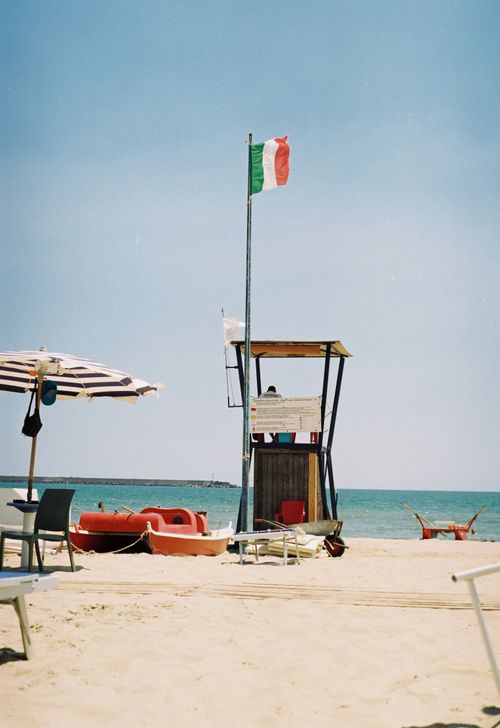 Free Relaxing day at an Italian beach with a lifeguard tower and colorful umbrellas. Stock Photo