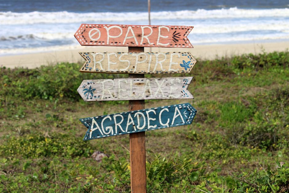 Vibrant handmade signs on Guaratuba beach guide visitors to pause, breathe, relax, and express gratitude.