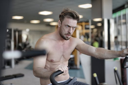 A determined man working out on exercise equipment indoors in a gym setting.