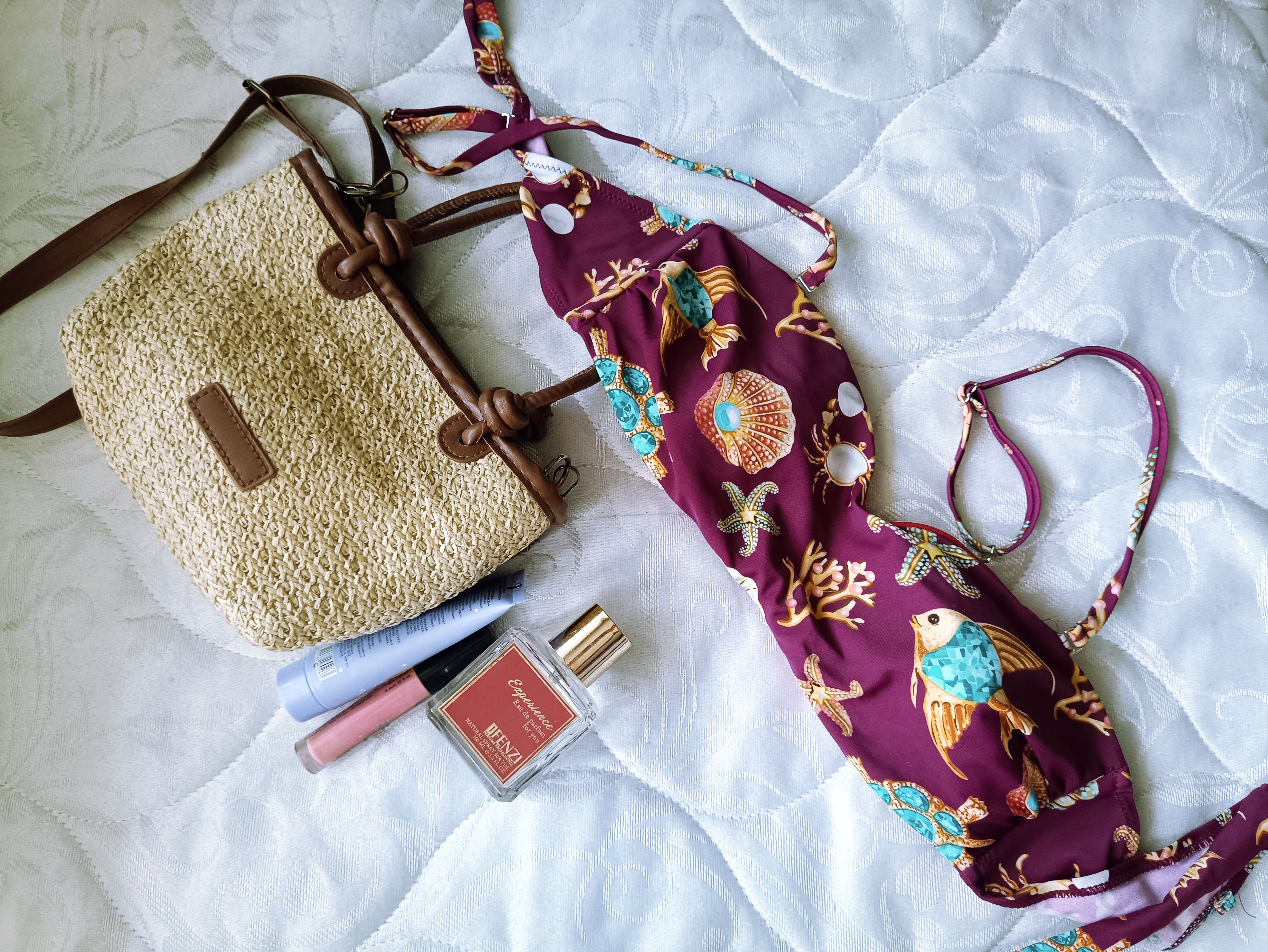 A vibrant, summery flat lay with a bikini, straw bag, and cosmetics, perfect for vacation vibes.