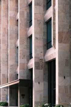 Close view of a modern building exterior with stone textures and vertical patterns.