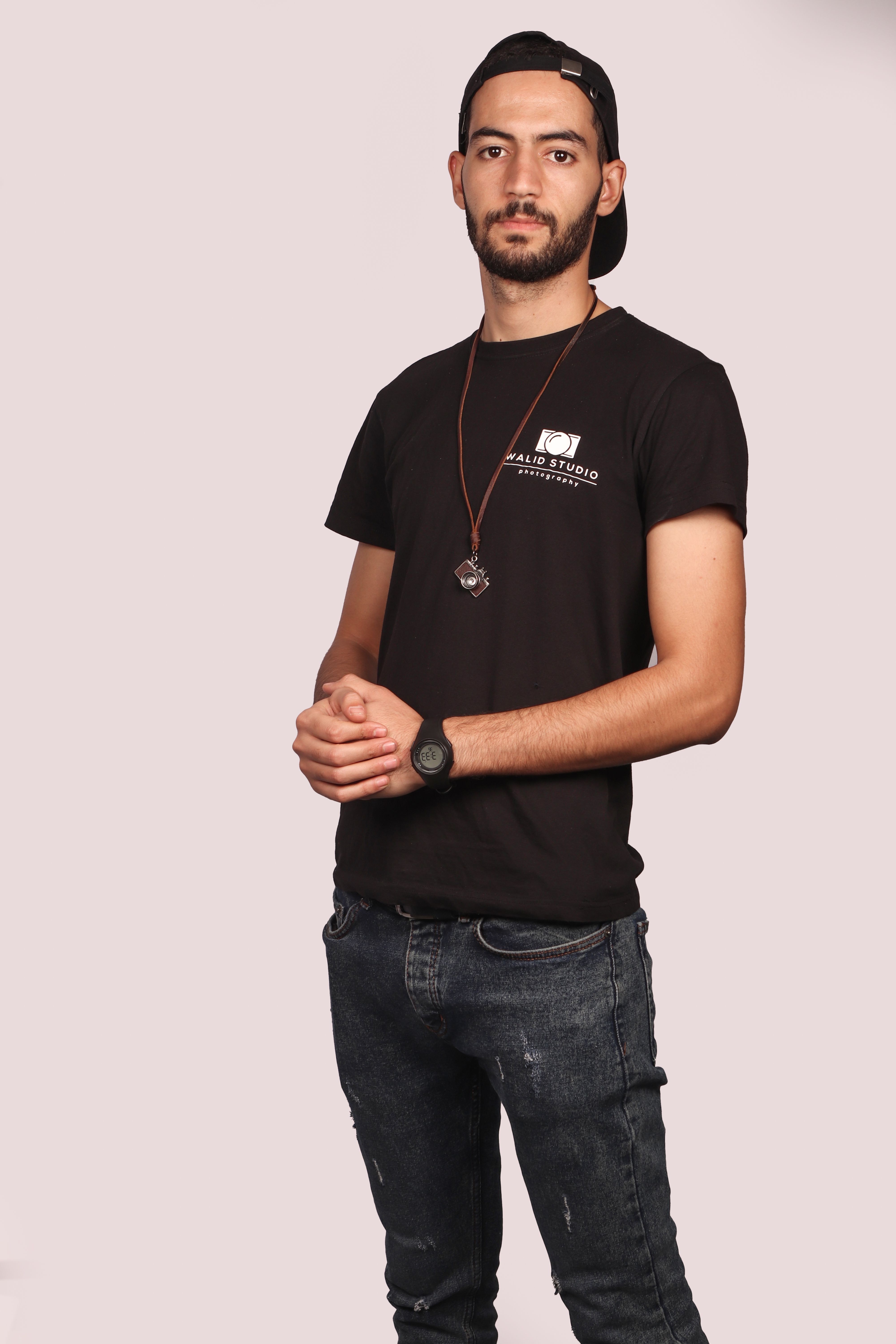 Young man in casual attire posing confidently against a neutral background.