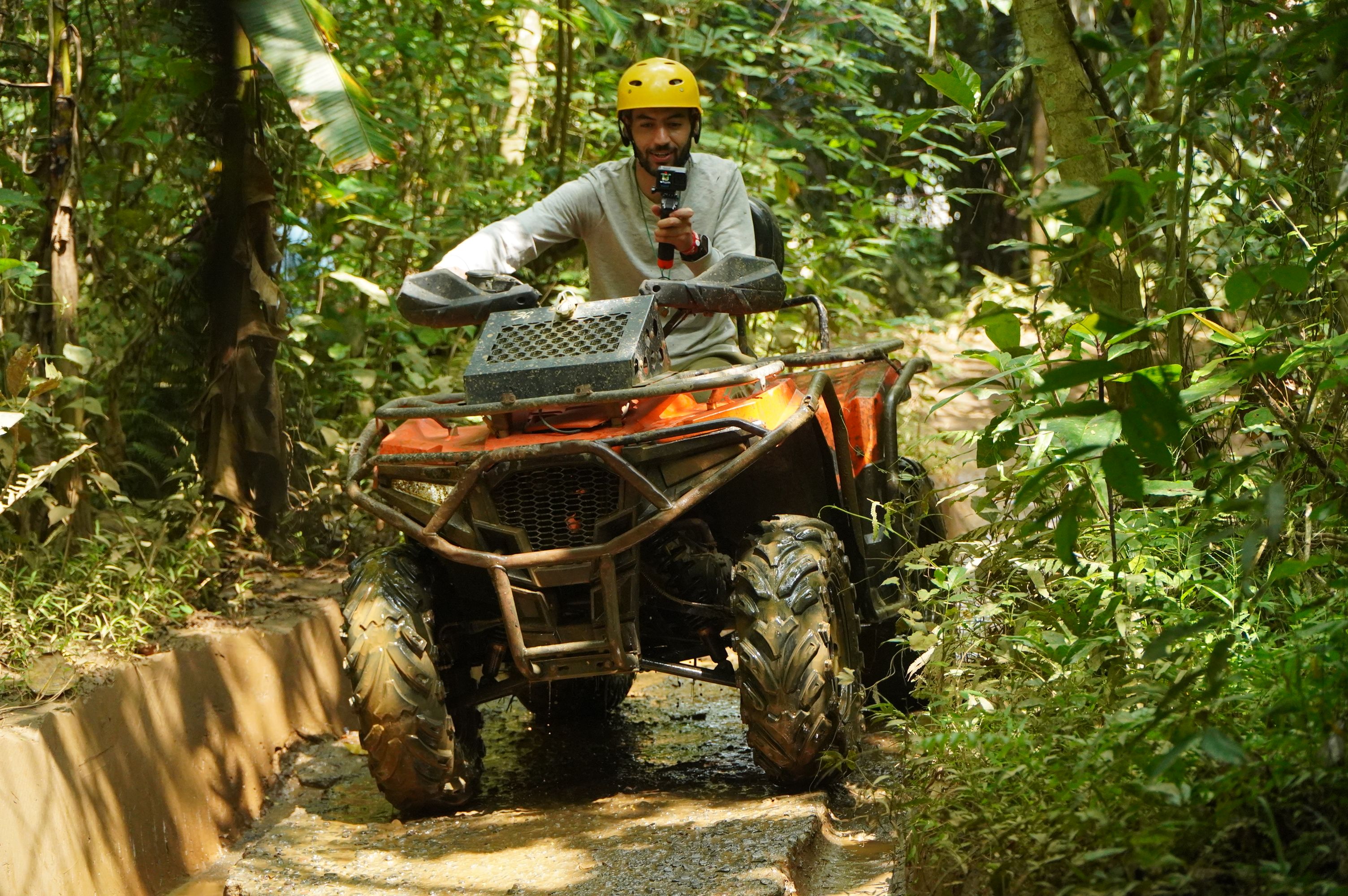 Man riding ATV through dense jungle trail, capturing the thrill of adventure.