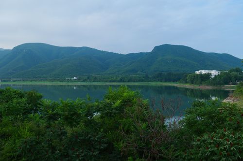 Free A tranquil view of lush green mountains reflected in a calm lake. Stock Photo