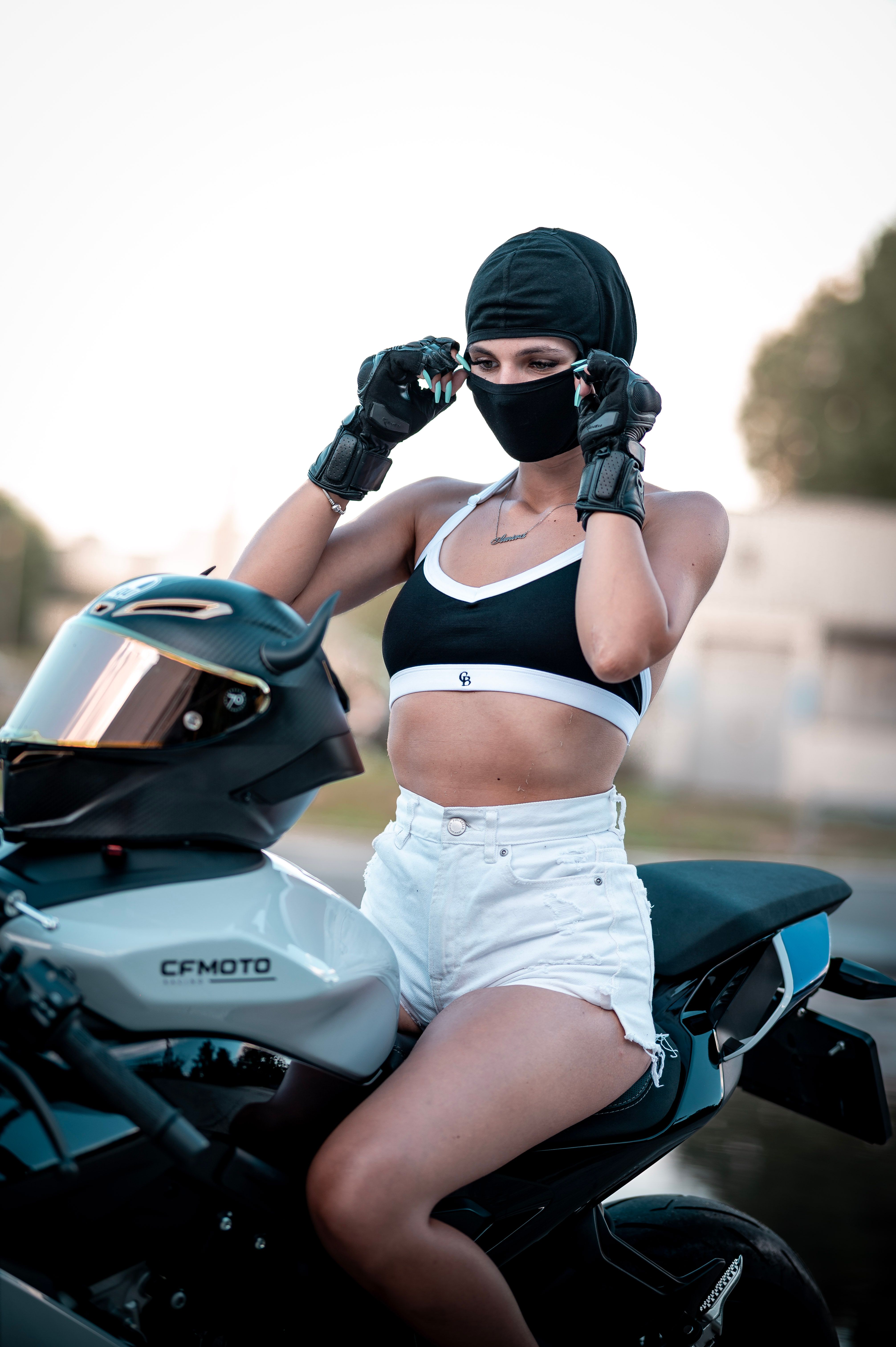 Woman in biker attire preparing to ride a motorcycle outdoors with a focused expression.