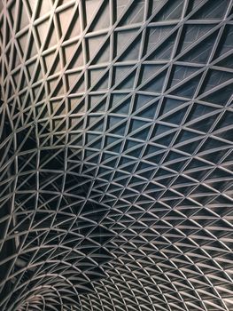 Intricate metal lattice ceiling at King's Cross Station, London, showcasing modern architectural design.