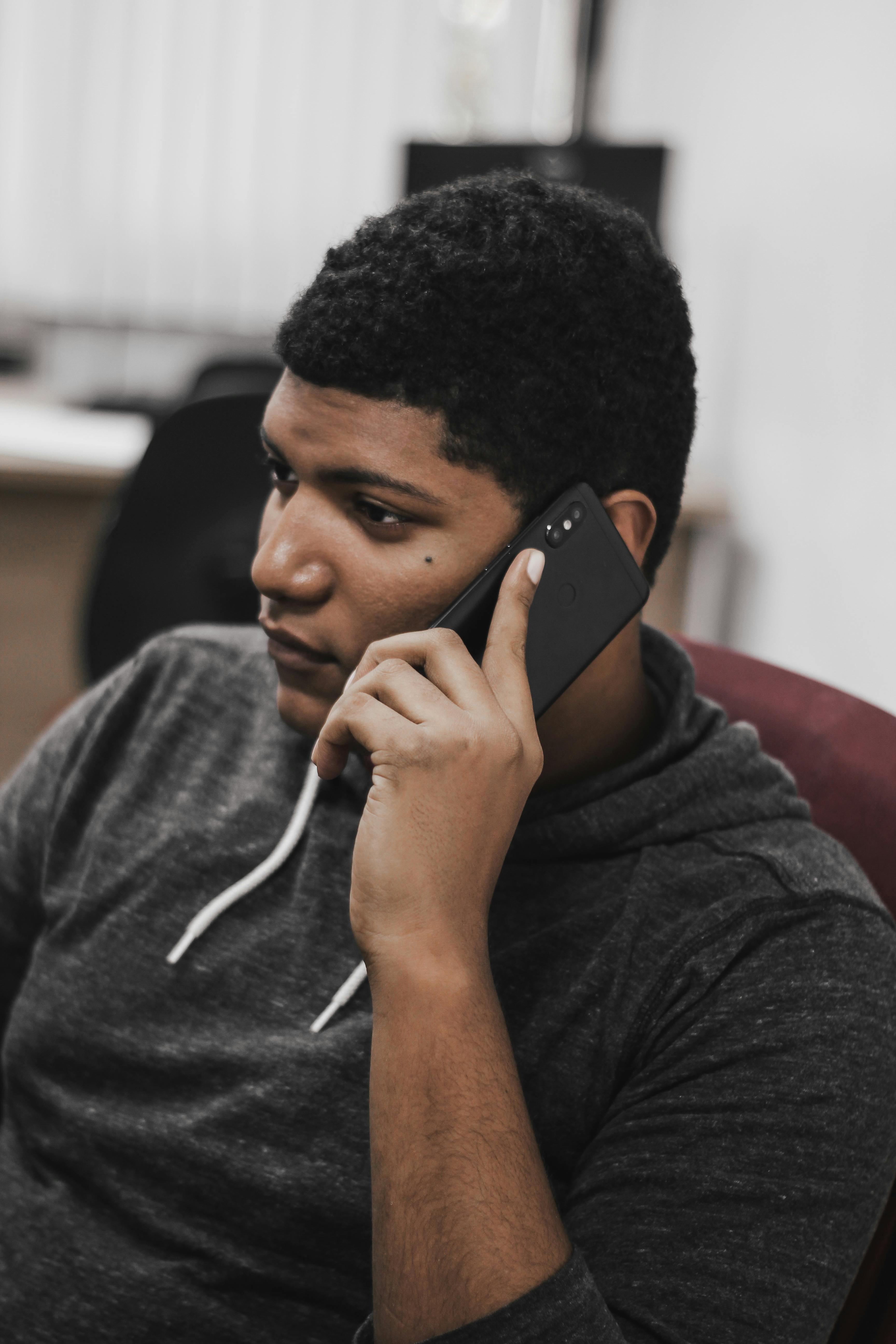 thoughtful young man talking on smartphone in workplace