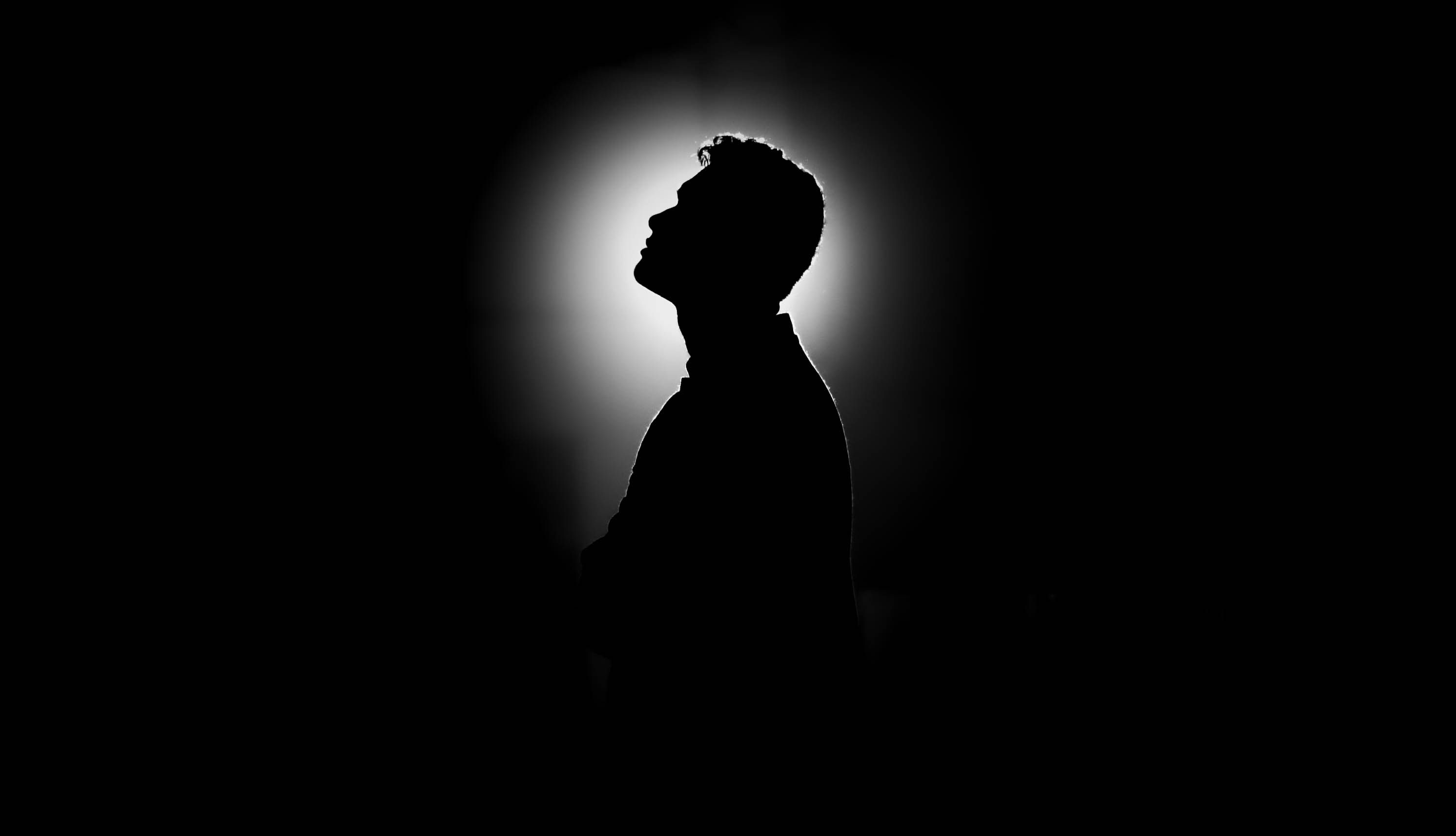 Silhouette of a man with dramatic lighting and a dark background creating a mysterious mood.
