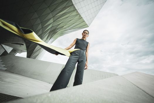 Contemporary fashion portrait of a woman against a geometric architectural backdrop.