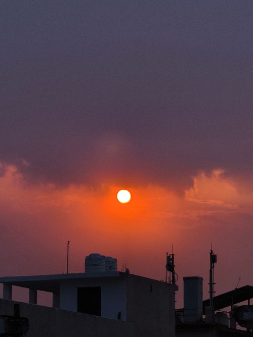 Free Breathtaking sunset over Delhi cityscape with vibrant orange sky and silhouetted buildings. Stock Photo